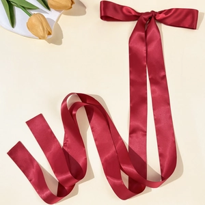 Detail view of wine red satin bow hairclip with long flowing silk ribbon texture