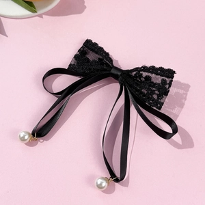Detail of black floral lace bow hair clip with satin ribbons and white faux pearls