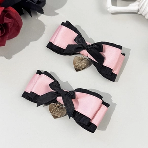 Detailed macro of pink and black layered Lolita bow hair clips with gold heart charms