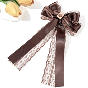 Detail of dark brown satin bow hair clip with elegant lace edges and bear resin ornament