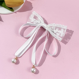 Elegant white lace bow hair clip with silk ribbons and faux pearl pendants on pink backdrop