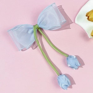 Detail van de lichtblauwe tulpenstrik haarclip van organza met groene satijnen kwastjes en bloemen