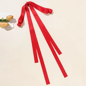 Dettaglio del fermaglio per capelli con fiocco in raso rosso e nastri lunghi