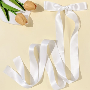 Detail showing high-gloss white satin bow hair clip with long flowing ribbons for hair