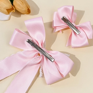 Pink satin bow hair clips set with white lace detail and elegant floral background