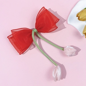 Detail van rode organza strik haarklem met roze tulpenhangers en groene satijnen lint