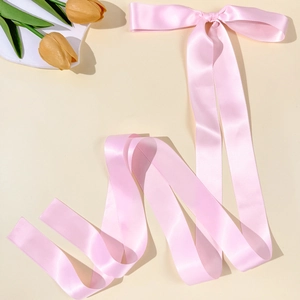 Detail of light pink satin ribbon hair clip with long streamers and smooth glossy finish
