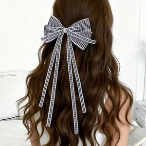 Détail de la pince à cheveux à nœud quadrillé avec rubans et strass sur cheveux