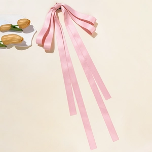 Dettaglio del fermaglio per capelli con fiocco in raso rosa e lunghi nastri eleganti