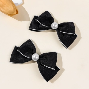 Close-up of elegant black fabric bow hair clips with white pearls and stitched edges
