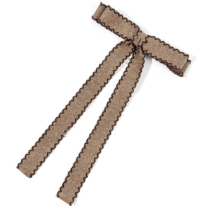 Elegant brown fabric bow hair clip with black zigzag stitching and textured material