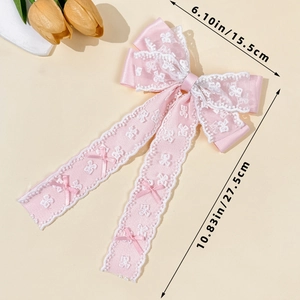 Detail view of pink lace bow hair clip with floral embroidery and long ribbons