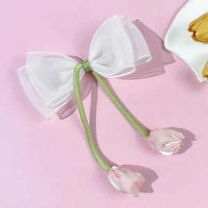 Detail van witte organza strik haarklem met roze zijden tulpen en een groen lintje