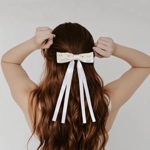 Close-up of cream lace bow hair clip with long satin ribbons on brown wavy hair