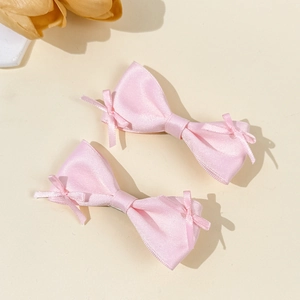 Close-up of a pair of sweet pink satin bow hair clips with elegant ribbon accents