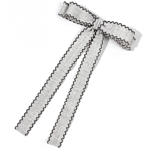 Detailed macro view of the grey fabric bow hair clip with black scalloped edge stitching