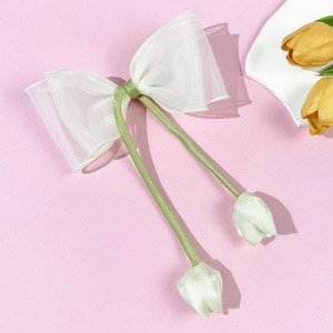 Detail van witte organza haarspeld met groene linten en kleine tulpvormige hangers