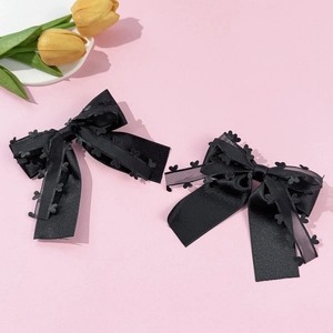 Détail de pinces à cheveux en satin noir avec dentelle à motif cœur sur fond rose
