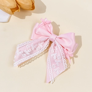 Close-up of pink ribbon hair clip with delicate white lace and elegant satin textures