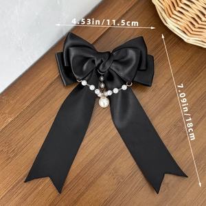 Dettaglio del fiocco in raso nero con perle che mostra dimensioni di 11,5 cm per 18 cm