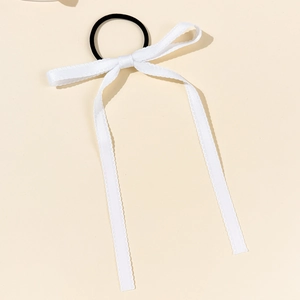 Détail d'un chouchou à nœud blanc avec de longs rubans et un élastique noir pour cheveux