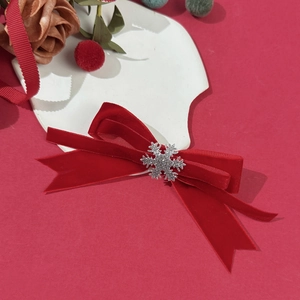 Close-up of red velvet Christmas bow hair clip with a glittery silver snowflake center
