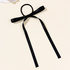 Détail d'un chouchou à nœud en soie noire avec bords en dentelle et longs rubans fluides