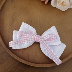 Pince à cheveux nœud vichy rose avec dentelle et ruban de soie sur une assiette en bois