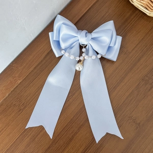 Dettaglio del fiocco in raso azzurro con elegante catena di perle e ciondolo a perla