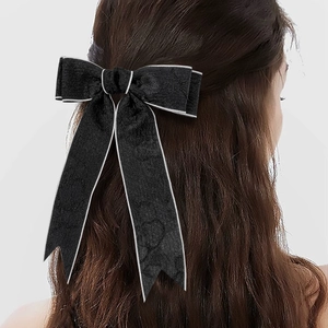 Détail de la grande barrette noeud en velours noir avec bordure argentée et rubans