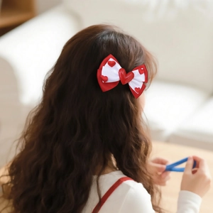 Sweet double-layer red and white bow hair clip with 3D hearts worn on wavy brown hair