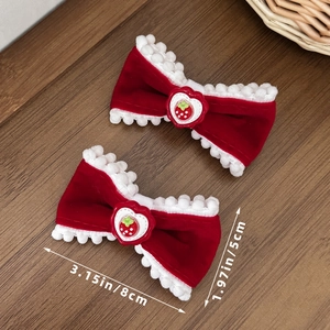 Detail view of two red velvet bow hair clips with strawberry heart and 8cm x 5cm dimensions
