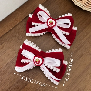 Detail of red velvet bow hair clips with white pom-pom lace and strawberry heart charms