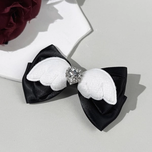 Detail van zwarte satijnen strik met witte pluche vleugels en een hartvormige strass