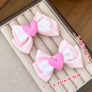 Close-up of pink and white ribbon bow hair clips with heart detail and measurements