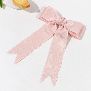 Détail d'un nœud papillon en satin jacquard rose avec de longs rubans et texture