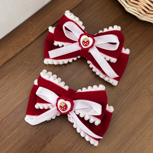 Red velvet Christmas bow hair clips with strawberry hearts and white pom-poms on wood