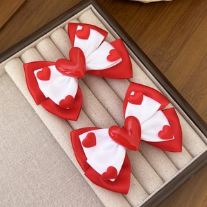 Detail of red and white double-layered bow hair clips with resin heart decorations