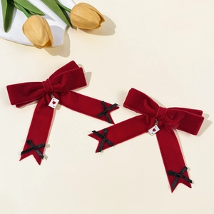 Close-up of velvet bow hair clips with Ace of Hearts pendants and tulip background