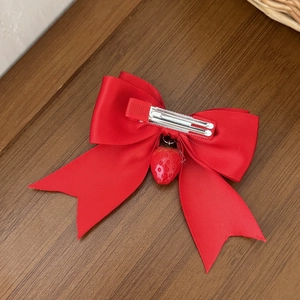 Détail d'un nœud papillon en satin rouge avec un pendentif fraise sur une surface en bois