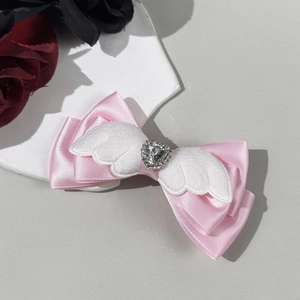 Detail van roze satijnen haarclip met witte pluche vleugels en hartvormige strass