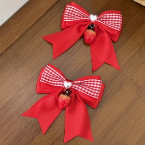 Détail de barrettes à nœuds à carreaux rouges avec perles de cœur et fraises