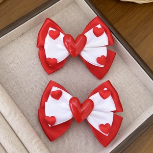Detail of red and white layered bow hair clips with 3D heart accents for girls