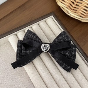 Close-up of a French houndstooth bow hair clip with a sparkling heart rhinestone center