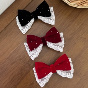 Elegante Haarklammern mit Samt- und Spitzenschleifen in Schwarz und Rot auf Holzgrund