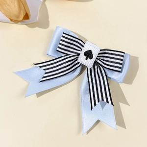 Detail of blue and striped ribbon bow hair clip with a spade embroidery patch