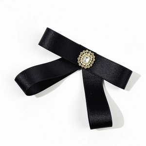 Vue détaillée du nœud en satin noir avec dentelle dorée et ornements de perles