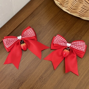 Détail de barrettes à nœuds écossais rouges avec perles de cœur et fraises