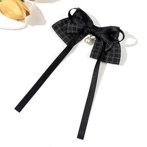 Close-up of black satin bow hair clip featuring checkered mesh and pearl pendant detail