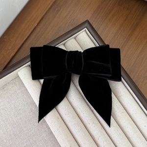 Detailed view of premium black velvet bow hair clip on a textured jewelry tray